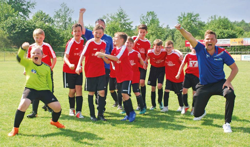 Équipe de jeunes footballeurs et entraîneur célébrant la victoire au tournoi Slagharen Trophy