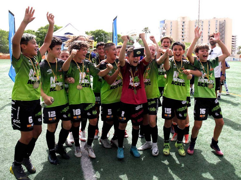 Youth football team jubilant with trophy, celebrating at Mallorca International Football Cup.