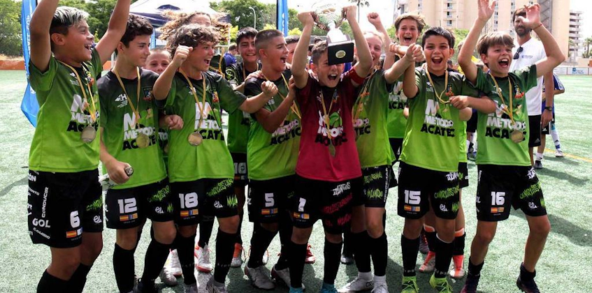 Rõõmsameelne noorte jalgpallimeeskond tõstab trofeed, tähistades võitu Mallorca Rahvusvahelisel Jalgpallikupil.