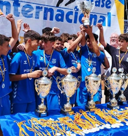 Unga fotbollsspelare firar seger med pokaler på Madrid International Cup