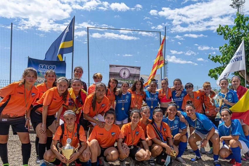 Women's soccer team with a trophy at International Summer Cup, flags of nations in the backdrop.