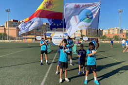 मैदान पर स्पेन और यूरोपीय संघ के झंडे के साथ युवा फुटबॉल खिलाड़ी।