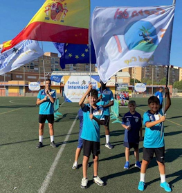 Young soccer players holding Spanish and EU flags on the soccer field.