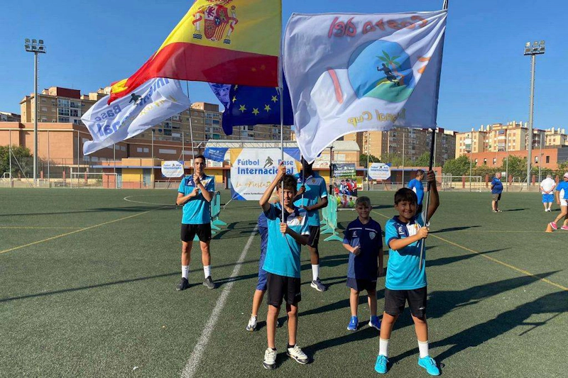 Young soccer players holding Spanish and EU flags on the soccer field.