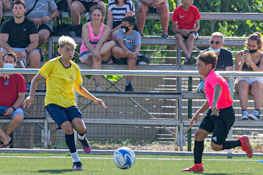 Giovani calciatori in azione durante una partita alla Salou Youth Cup con spettatori sullo sfondo.
