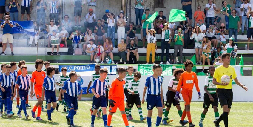 Echipe de fotbal juniori intră pe teren cu arbitrii și spectatorii în tribune la turneul de vară Miranda Cup.