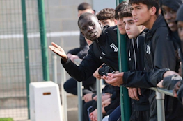 Jovens jogadores de futebol em agasalhos da Juventus focados no jogo, com um deles gesticulando explicativamente.