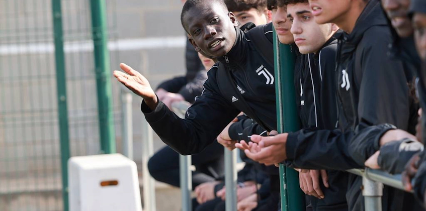 Молодые футболисты в спортивных костюмах Juventus сосредоточены на игре, один из них объясняет жестами.