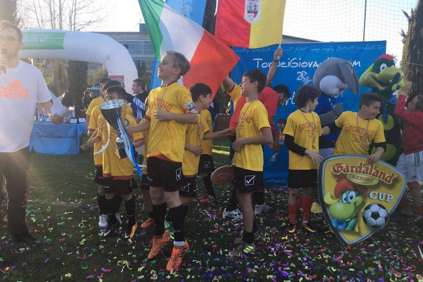 Youth football team in yellow jerseys celebrating victory at Gardaland Cup with confetti.