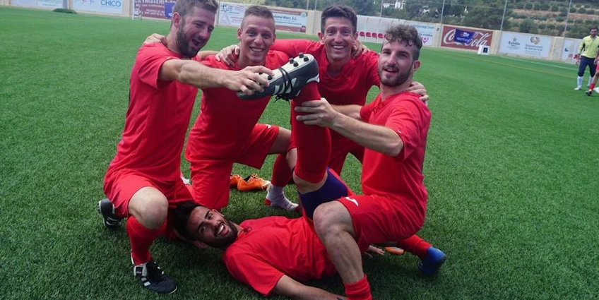 Soccer team in red jerseys celebrating a victory at Ibiza Football Fun tournament