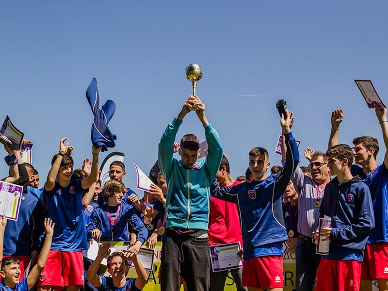 Labdarúgócsapat ünnepli a győzelmet trófeával a Salonica Soccer Cupon