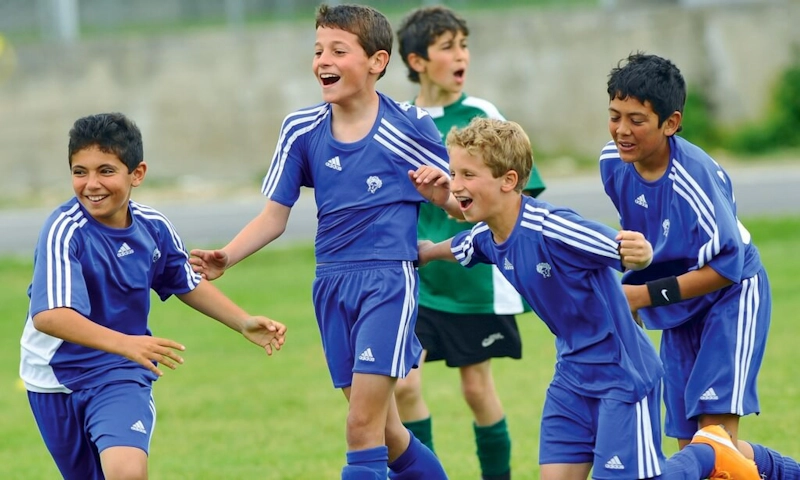 Jovens jogadores de futebol comemorando gol no torneio Trofeo Malgratense