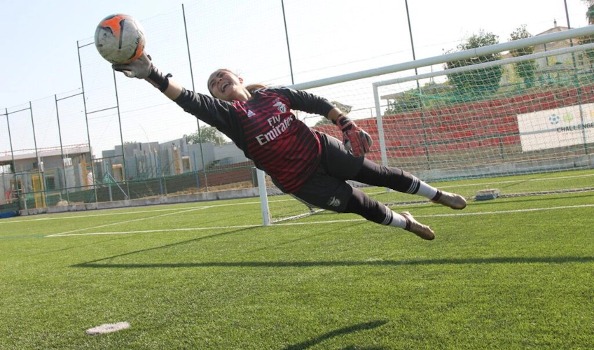 Kapus az Emirates csapatmezében labdavédést végez egy focimeccsen