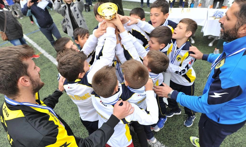 युवा फुटबॉलर्स टूर्नामेंट में ट्रॉफी के साथ जीत का जश्न मना रहे हैं