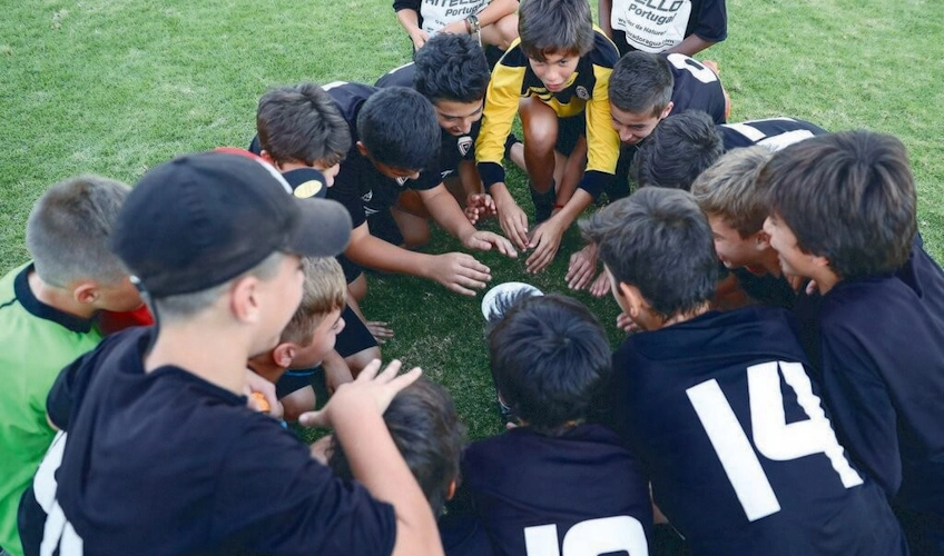 Młodzieżowa drużyna piłkarska podczas omawiania taktyki na Młodzieżowym Pucharze Lizbony