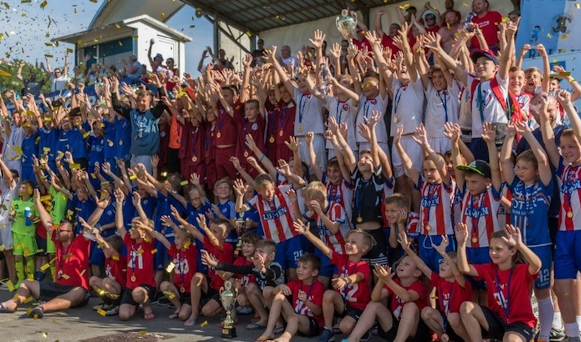 Young footballers and coaches celebrate victory at football tournament
