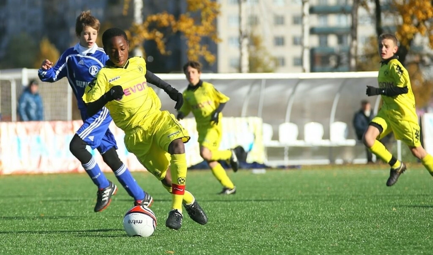 Tineri fotbaliști în echipamente strălucitoare jucând într-un turneu