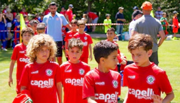Kırmızı formalarıyla genç futbolcular Pyrenees Cup turnuvasında sahada yürüyor.