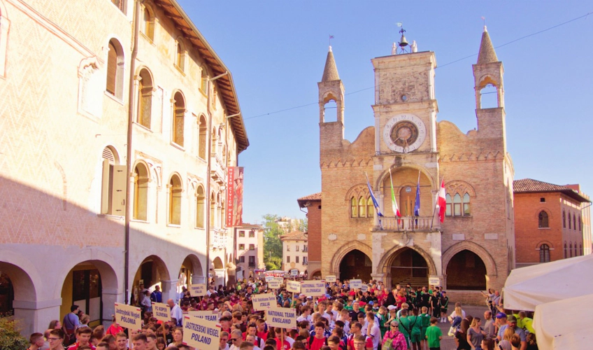 International youth football teams parading through a historic square during the Gallini Cup tournament.