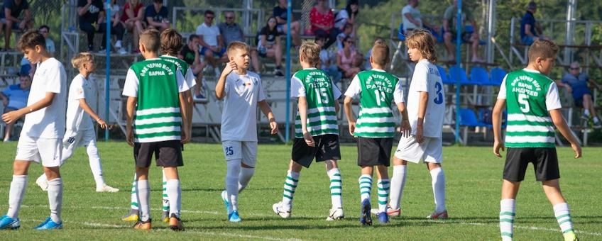Tineri fotbaliști în echipament alb și în dungi la turneul Cupa Juniorilor